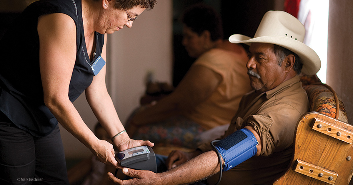 A woman taking a man's blood pressure