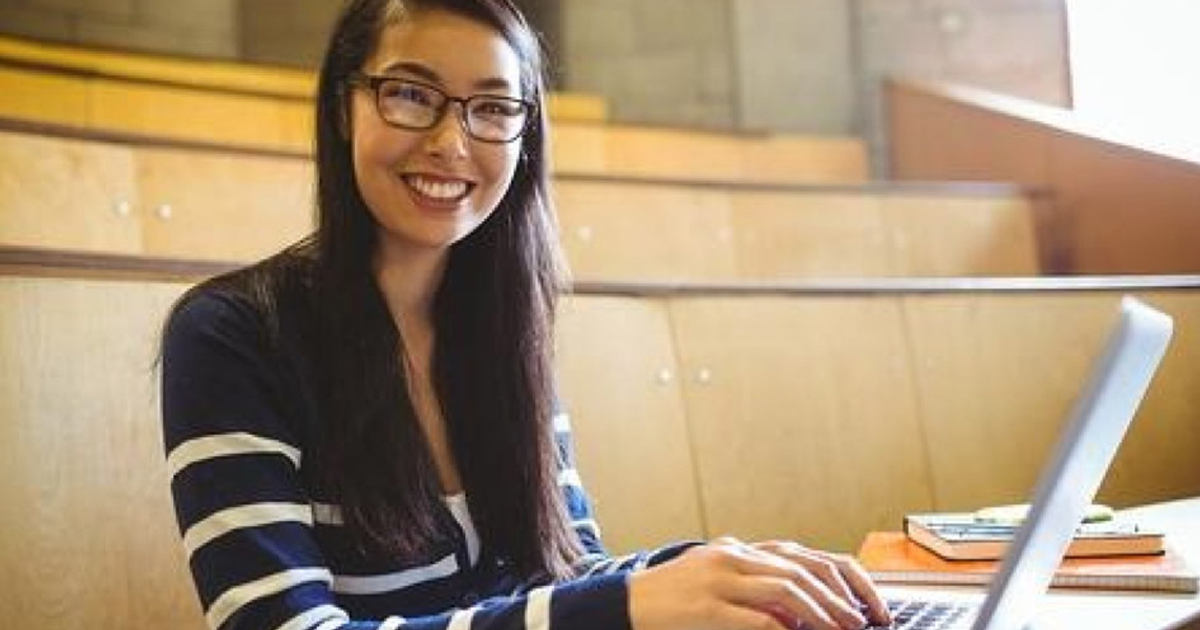 smiling-student-using-laptop-at