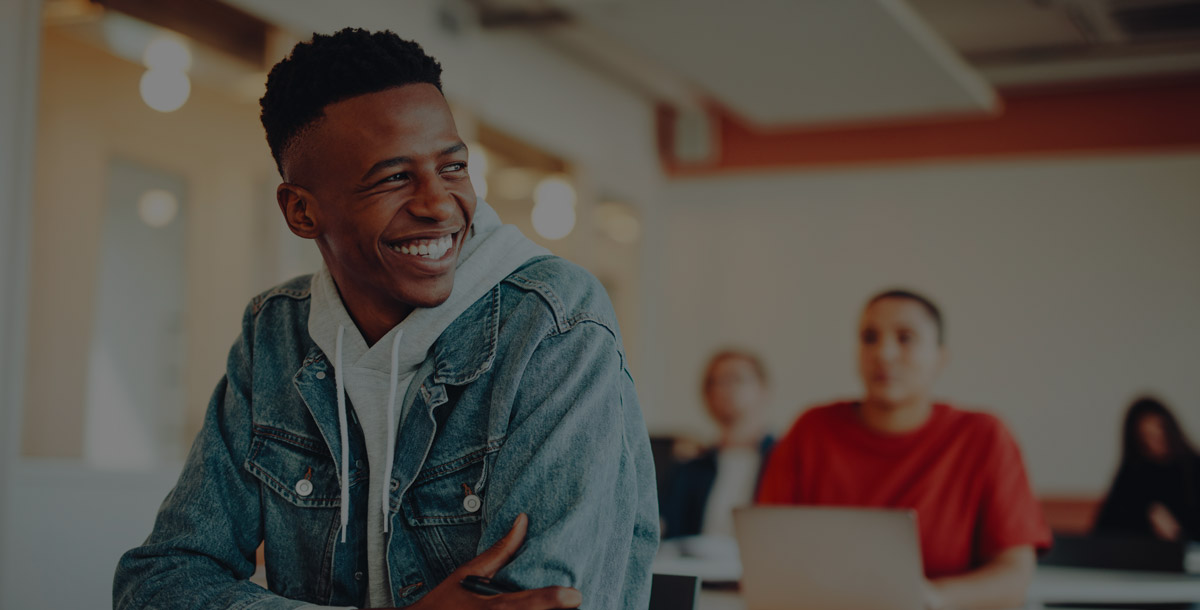 Young male student sitting in a college classroom smiling