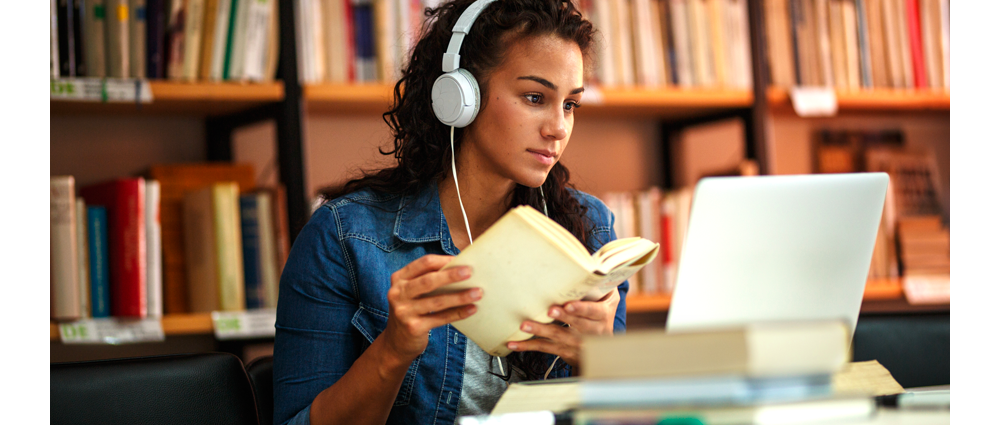 Female student with headphones studying in library